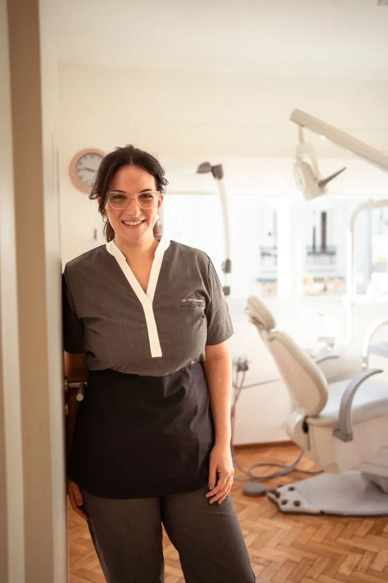 Od. Clara Rossello sonriendo con uniforme gris en consultorio